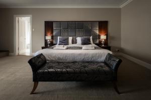 德里门Buchanan Arms Hotel & Leisure Club的一间卧室配有一张大床和黑色皮沙发