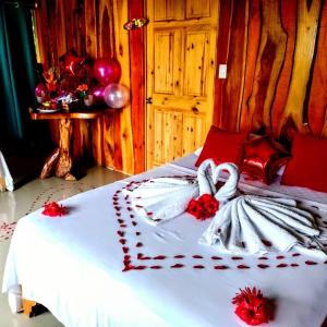 德雷克The Sunset Tucano Lodge的一张铺有白色床单和红色鲜花的床