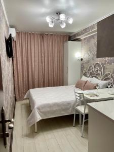 比什凯克Уютная комната-студия в центре Бишкека的一间卧室配有一张床铺和一张桌子,还设有一间厨房
