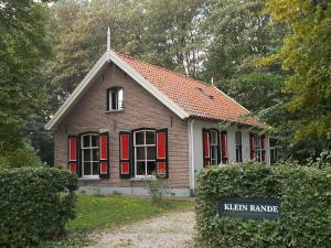DiepenveenHotel Gaia的一间设有红色百叶窗和标志的小房子