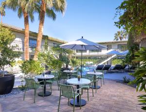 棕榈泉Descanso Resort, A Men's Resort的一个带桌椅和遮阳伞的庭院