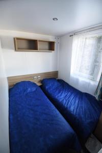 莱马特Mobil Home 8 personnes的一间卧室设有蓝色的床和窗户。