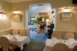 约尔阿赫尼斯联排别墅酒店和海鲜餐厅的一间带白色桌椅的餐厅和一间用餐室