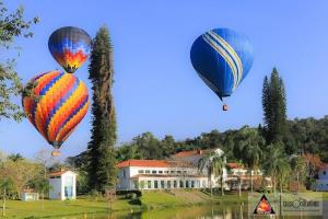 圣洛伦索Pousada do Ipê的三只热气球在房子上空飞行