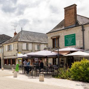 维朗德里Logis Auberge Le Colombien - Hôtel et Restaurant的坐在桌子上的人,在建筑物前用雨伞