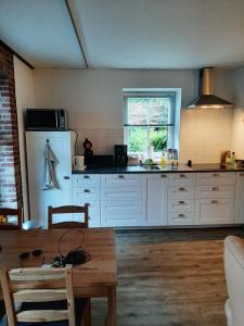 Vlagtwedde'T Wolthoes的厨房配有白色橱柜和木桌
