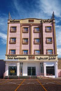 苏尔Arkan Al Barzah Hotel Apartment的一座大型粉红色建筑,设有酒店公寓