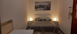 洛阿诺Residence Villa Chiara的一间小卧室,配有一张床和墙上的两盏灯