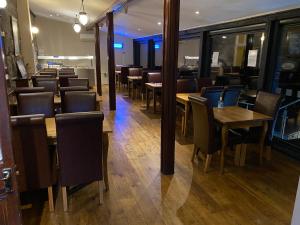 布莱奈费斯蒂尼奥格Grapes Hotel, Bar & Restaurant Snowdonia Nr Zip World的用餐室配有木桌和椅子