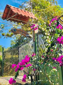 PejibayeHospedaje Luis & Ana的围栏前有粉红色花的街道标志