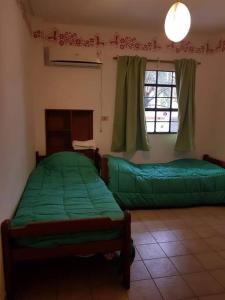 圣米格尔·德·图库玛Tu Lugar en Tucumán的一间卧室设有两张绿色的床和窗户