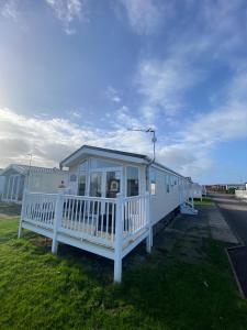 拉尔E3 is a 2 Bedroom 6 berth Lodge on Whitehouse Leisure Park in Towyn near Rhyl close to beach with decking and private parking space This is a pet free caravan的路边白色移动房屋