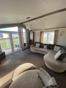 拉尔E3 is a 2 Bedroom 6 berth Lodge on Whitehouse Leisure Park in Towyn near Rhyl close to beach with decking and private parking space This is a pet free caravan的一间带两张沙发的客厅和一个阳台