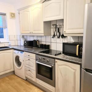 巴洛赫Levenside Holiday Apartment, Balloch, Loch Lomond的厨房配有白色橱柜、洗衣机和烘干机
