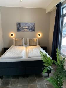 哈马尔Vikingskipet Hotell的一间卧室,配有一张带两盏灯和一根植物的床