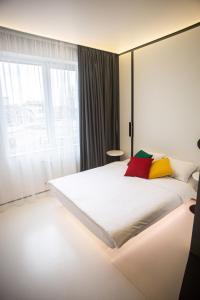 敖德萨Sunday Rooms的卧室配有一张带彩色枕头的大型白色床。