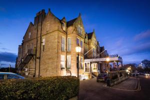 爱丁堡The Bruntsfield Hotel的一座古老的建筑,前面有停车位