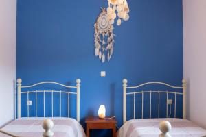 SkouloúfiaRural Residence的一间蓝色卧室,配有两张床和蓝色的墙壁