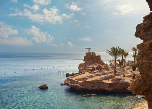 沙姆沙伊赫梦海滩度假村- 沙姆沙伊赫的海滩上设有椅子和遮阳伞,还有大海