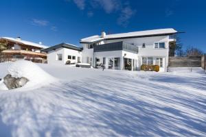 蒂罗尔-泽费尔德Villa Mama - Luxus und Lebensfreude的前面有一堆积雪的白色房子