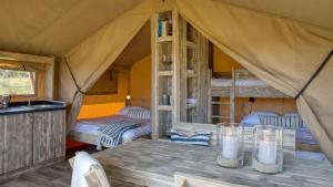 布劳沃斯港Buitenplaats de Oorsprong的帐篷配有两张床和一张带蜡烛的桌子