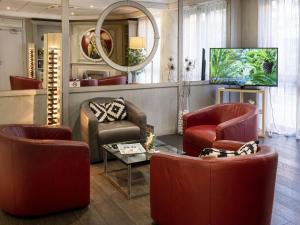 尼斯尼斯海滨酒店的一间设有红色椅子和电视的等候室