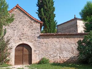 GinalsLes granges de l abbaye的一座古老的石头建筑,有门和树木