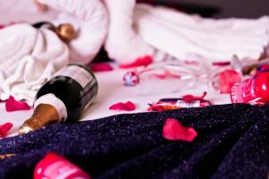 MatolaHotel Al-Khalil Matola的一瓶葡萄酒,坐在红色玫瑰床上