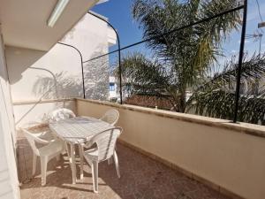 托雷圣乔万尼乌Appartamento Ghirigoro 1的阳台配有桌椅和棕榈树。