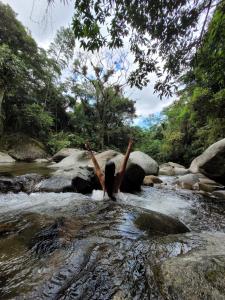 瓜皮米林Pousada Camping dos Ypês的站在河里,手臂在空中的女人