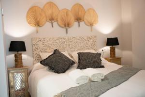 塞维利亚Apartamento Alma Sevilla的一间卧室配有一张带两个枕头和两个灯的床。