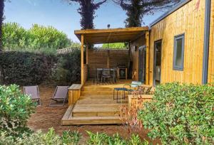 雷岛林滩Camping Le Suroit的房屋设有木甲板、椅子和桌子