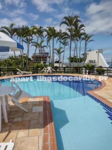 马蒂尼奥斯Apto Cond Ilhas do Caribe - Pr - Beira Mar的一个带桌子和棕榈树的大型游泳池
