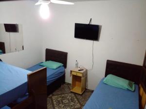 贝洛奥里藏特Hostel Gerais的客房设有两张床和一台平面电视。