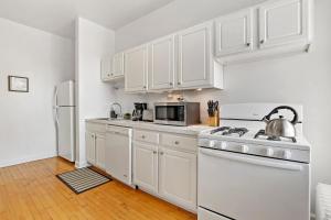 芝加哥Stylish and Expansive 2BR Apt with Balcony - Buckingham 3的厨房配有白色橱柜和白色炉灶烤箱。