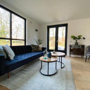 EwijkHuisje Hygge - luxe bungalow met grote tuin的客厅配有蓝色的沙发和2张桌子