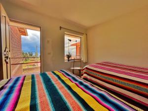 奥科苏尤Richar’s home - experience Amantani with my family的一间卧室配有一张色彩缤纷的条纹床和一扇窗户。
