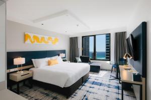 黄金海岸voco Gold Coast, an IHG Hotel的一间酒店客房,配有一张床和一台电视