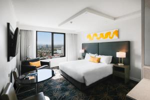 黄金海岸voco Gold Coast, an IHG Hotel的酒店客房,配有一张床、一张桌子和椅子