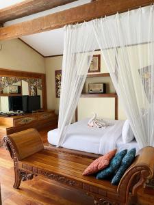 伦邦萨普里迪咖啡馆、画廊及度假酒店的一间卧室配有一张带长凳的天蓬床
