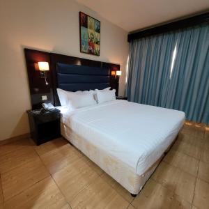 阿布扎比斯特朗德酒店的一间卧室配有一张白色大床和蓝色床头板