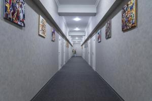塔什干THE TIME HOTEL的走廊上设有长长的过道,墙上挂有绘画作品