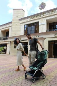 阿德勒Golden Dolphin的一名女人和一个男人在建筑物前推一辆婴儿车