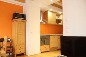 博尔戈Trentino Apartments - Il Gufo Vacanze的厨房设有橙色墙壁、木制橱柜和电视。