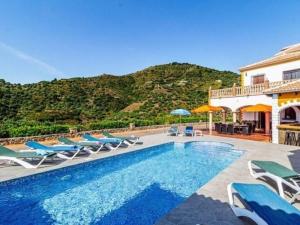 赛阿隆加Belvilla by OYO Villa Javier的一座带游泳池和椅子的别墅,一座山