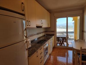 福斯Dúplex en 1ª línea de playa的带冰箱的厨房、桌子和阳台