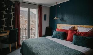 巴斯洛内特Hotel Spa Azteca Barcelonnette的一间卧室配有一张带色彩缤纷枕头的床和窗户。