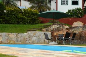拉夫拉斯诺瓦斯Pousada Villa Verde的游泳池旁配有遮阳伞的桌椅