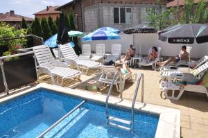 韦林格勒Family Hotel Dalia的游泳池配有椅子和遮阳伞,客人亦可坐在游泳池内
