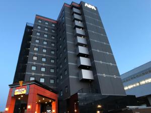 上越市APA Hotel Joetsu Myoko-Ekimae的一座高大的黑色建筑,上面有标志